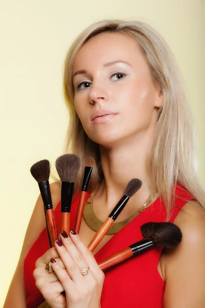 Procedimentos de beleza, mulher mantém pincéis de maquiagem perto do rosto . — Fotografia de Stock