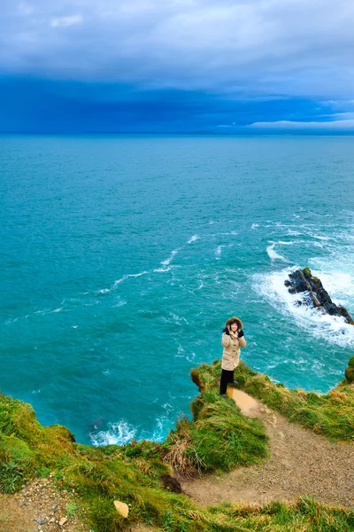 Kobieta stojąca na skalnym klifie przy oceanie Co. Cork Ireland — Zdjęcie stockowe