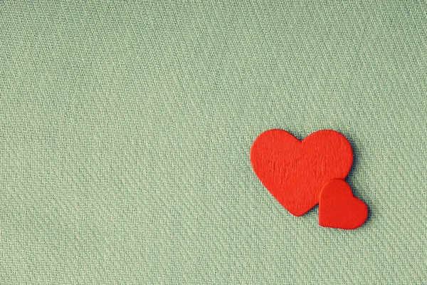 Red wooden decorative hearts on green cloth background. Royalty Free Stock Photos