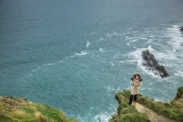 Woman standing on rock cliff by the ocean Co. Cork Ireland — Stock Photo, Image