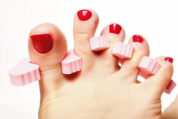 Pedicure pé aplicando unhas vermelhas sobre branco — Fotografia de Stock