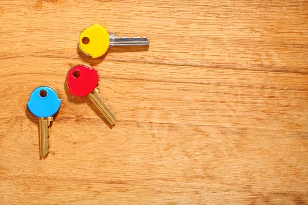 Huis sleutels met kleurrijke kunststof jassen caps op tafel — Stockfoto