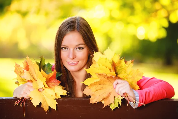Temporada de otoño. Retrato mujer niña sosteniendo hojas otoñales en el parque —  Fotos de Stock