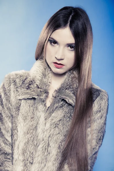 Portrait of girl with long hair. Young woman in fur coat on blue. — Stock Photo, Image