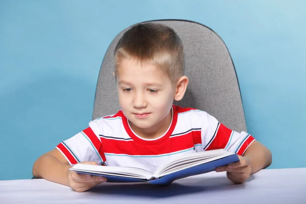Criança menino criança lendo um livro sobre azul — Fotografia de Stock