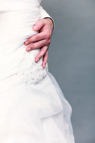 Closeup shot of wedding dress and groom hand — Stock Photo, Image
