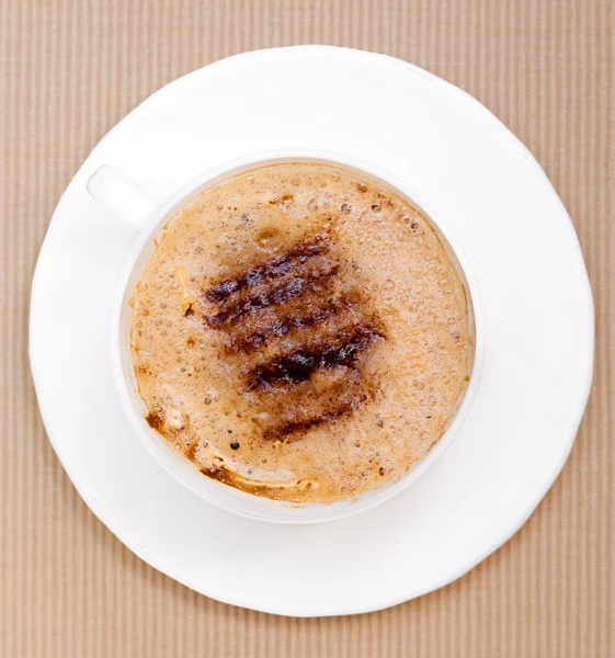 Weiße Tasse Kaffee Heißgetränk mit Schaum auf braunem Hintergrund — Stockfoto