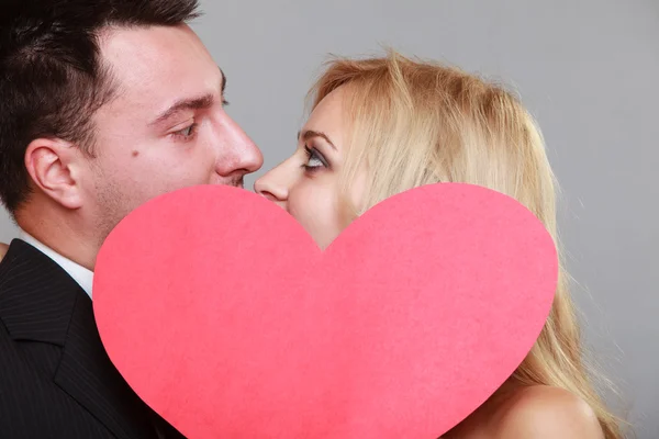 Happy bride and groom kissing behind red heart — Stock Photo, Image