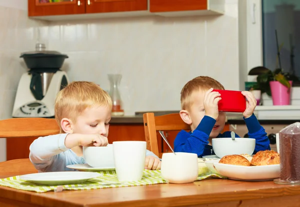Pojkar kids barn äta corn flakes spela med mobiltelefon — Stockfoto