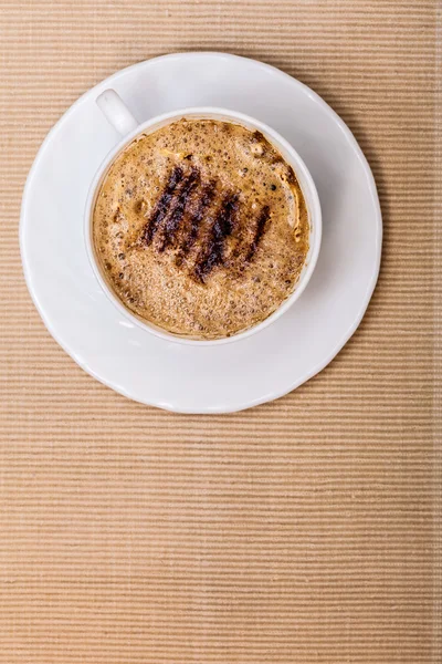 Weiße Tasse Kaffee Heißgetränk mit Schaum auf braunem Hintergrund — Stockfoto