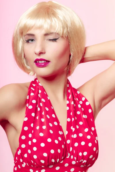 Pinup girl in blond wig and retro red dress winking. Vintage. — Stock Photo, Image