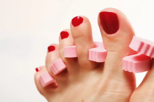 Voetpedicure aanbrengen van rode teennagels op wit — Stockfoto