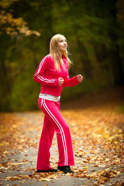 Blonde girl young woman running jogging in autumn fall forest park — Stock Photo, Image