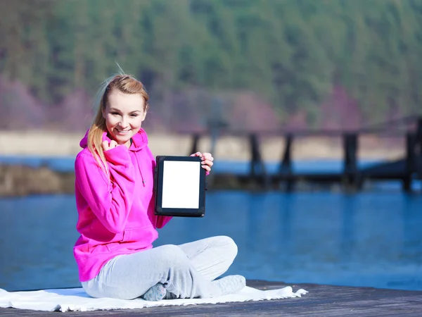 Woman teenage girl in tracksuit showing tablet on pier outdoor — Stock Photo, Image