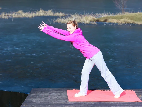 Woman teenage girl in tracksuit doing exercise on pier outdoor — Stock Photo, Image