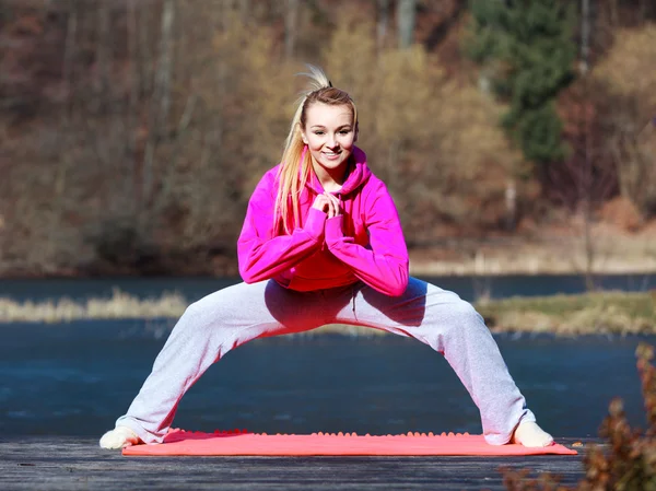 Woman teenage girl in tracksuit doing exercise on pier outdoor — Stock Photo, Image