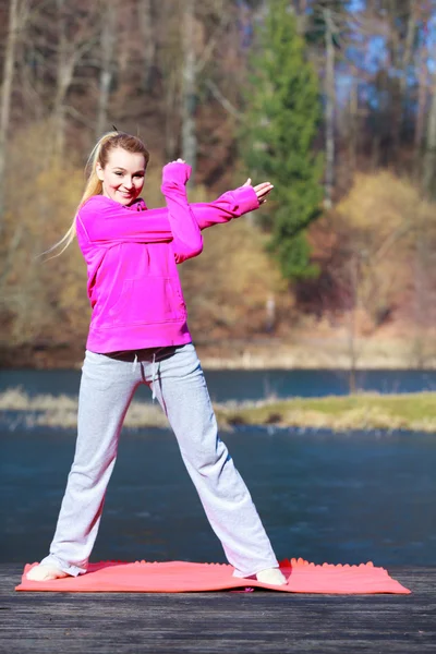 Woman teenage girl in tracksuit doing exercise on pier outdoor — Stock Photo, Image