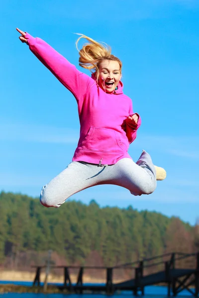 Cheerful woman teenage girl in tracksuit jumping showing outdoor — Stock Photo, Image