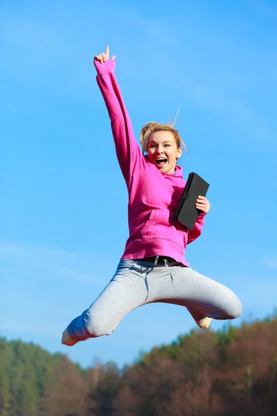 Vrolijke vrouw tienermeisje springen met tablet buiten — Stockfoto