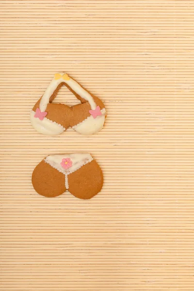 Yellow pink bikini shape gingerbread cake cookie on bamboo mat — Stock Photo, Image