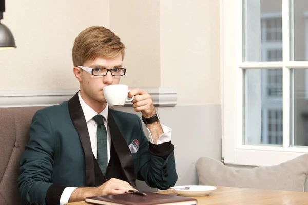 Jovem bonito homem elegante no café com café — Fotografia de Stock