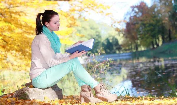 Młoda dziewczyna w jesienny park czytanie książki — Zdjęcie stockowe