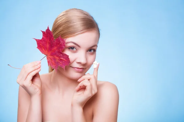 Huidverzorging. Gezicht van jonge vrouw meisje met rode esdoorn blad. — Stockfoto