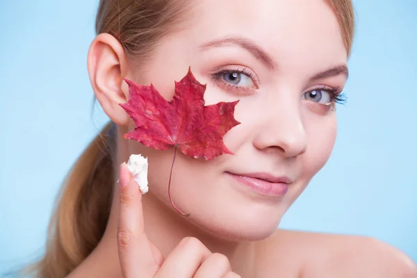 Huidverzorging. Gezicht van jonge vrouw meisje met rode esdoorn blad. — Stockfoto