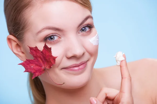 Huidverzorging. Gezicht van jonge vrouw meisje met rode esdoorn blad. — Stockfoto