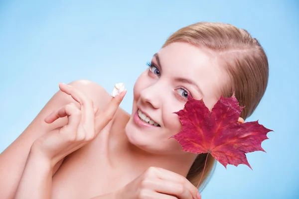 Huidverzorging. Gezicht van jonge vrouw meisje met rode esdoorn blad. — Stockfoto