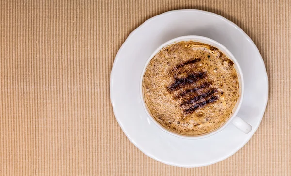 Copo branco café bebida quente com espuma no fundo marrom — Fotografia de Stock