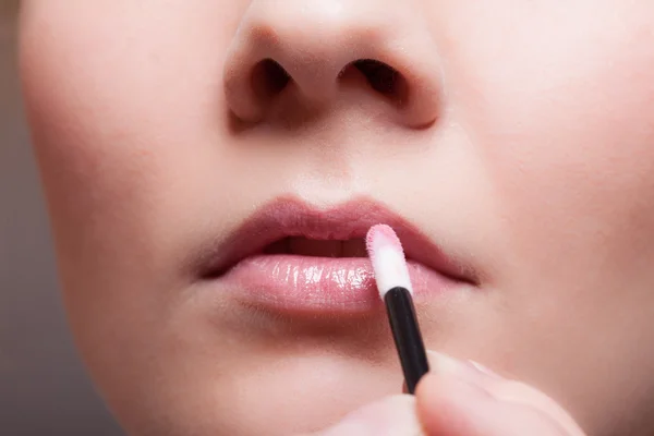 Maquillaje. Chica que aplica lápiz labial de brillo de labios en los labios. Parte de la cara . — Foto de Stock