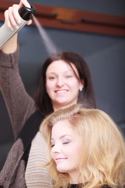 Hairstylist with hairspray and female client blond girl in salon — Stock Photo, Image