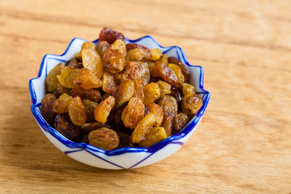 Diet healthy food. Raisin in bowl on wooden background — Stock Photo, Image