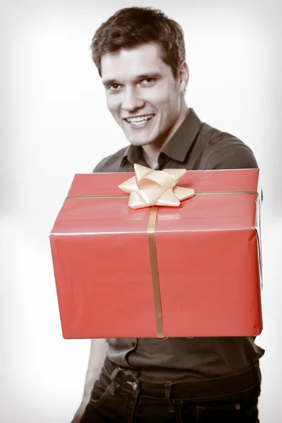 Holiday. Man giving red gift box with golden ribbon — Stock Photo, Image