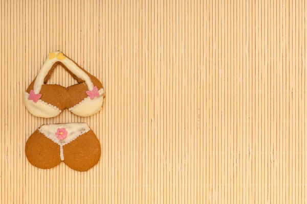 Yellow pink bikini shape gingerbread cake cookie on bamboo mat — Stock Photo, Image