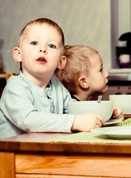 Due fratelli ragazzi bambini bambini che mangiano corn flakes colazione pasto del mattino a casa . — Foto Stock