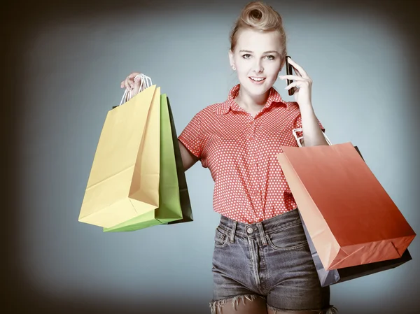 Pinup menina com sacos de compras chamando no telefone — Fotografia de Stock