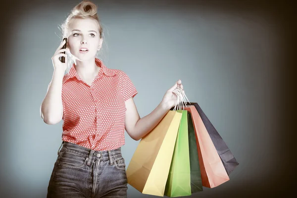 Pinup menina com sacos de compras chamando no telefone — Fotografia de Stock