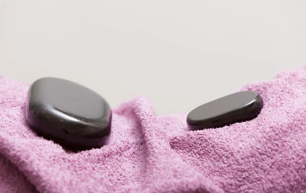 Spa koncept. Zen stone masáž lávovými na růžový ručník — Stock fotografie