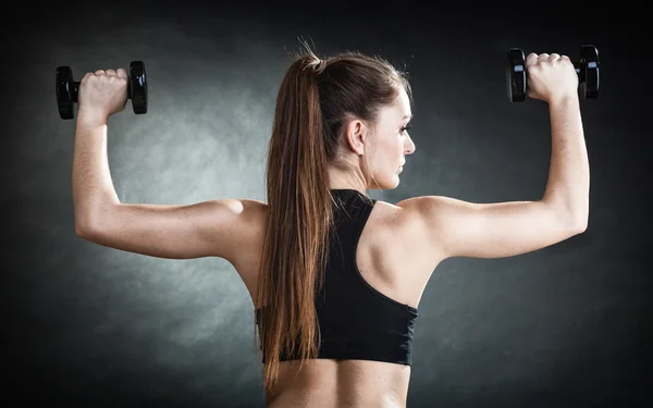 Fitness menina treinamento músculos do ombro levantando halteres visão traseira Imagem De Stock