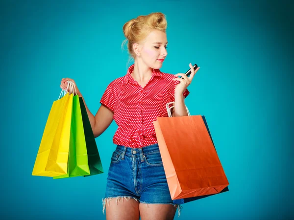 Pinup girl with shopping bags texing on phone — Stock Photo, Image