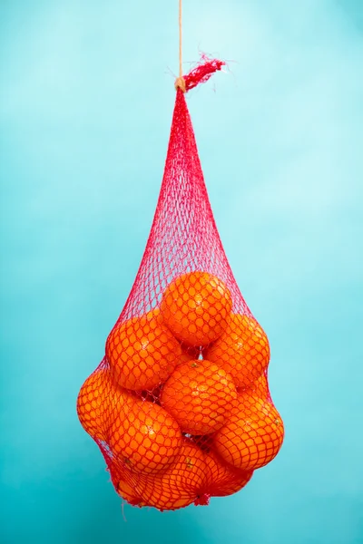 Färska apelsiner frukter i mesh från snabbköp — Stockfoto