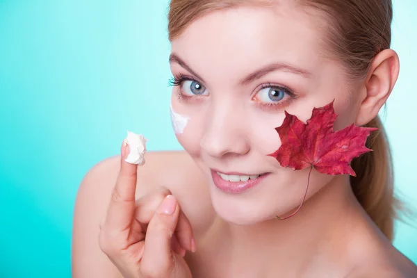 Huidverzorging. Gezicht van jonge vrouw meisje met rode esdoorn blad. — Stockfoto