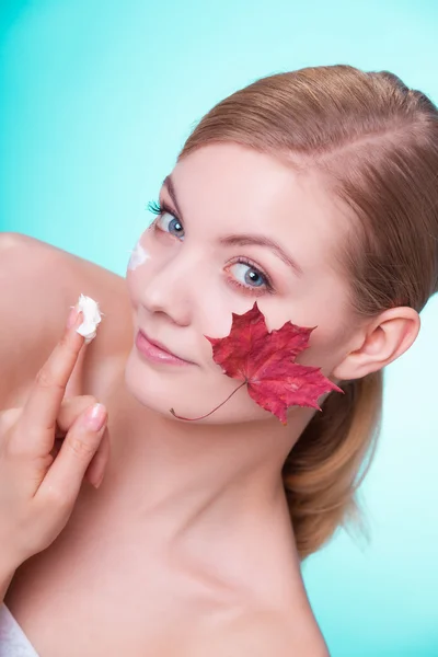 Huidverzorging. Gezicht van jonge vrouw meisje met rode esdoorn blad. — Stockfoto