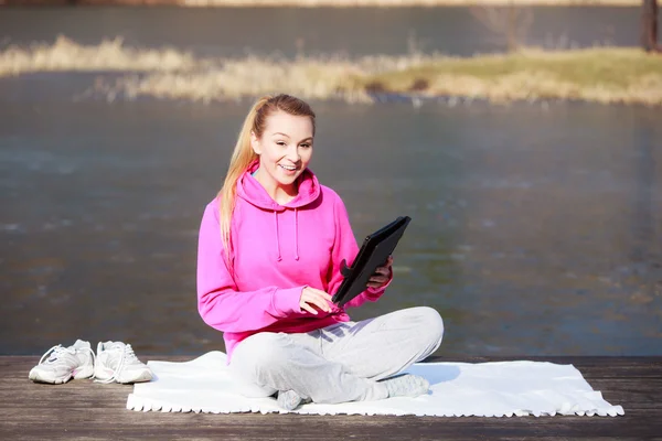 Woman teenage girl in tracksuit using tablet on pier outdoor — Stock Photo, Image