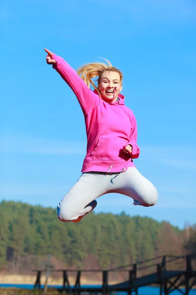 Cheerful woman teenage girl in tracksuit jumping showing outdoor — Stock Photo, Image