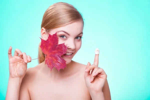 Soins de la peau. Visage de jeune femme fille avec feuille d'érable rouge. — Photo