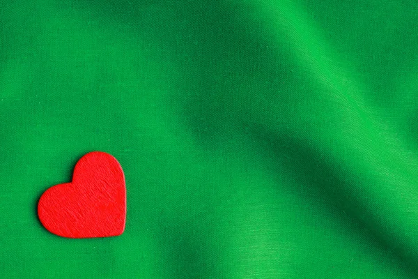 Red wooden decorative heart on green folds background. — Stock Photo, Image