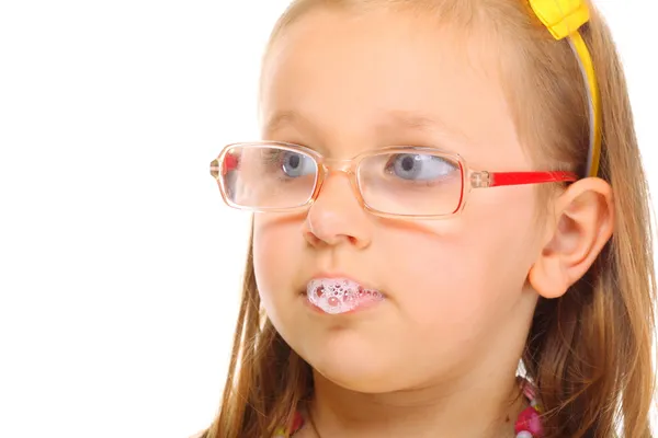 Close up little girl in glasses doing fun saliva bubbles — Stock Photo, Image
